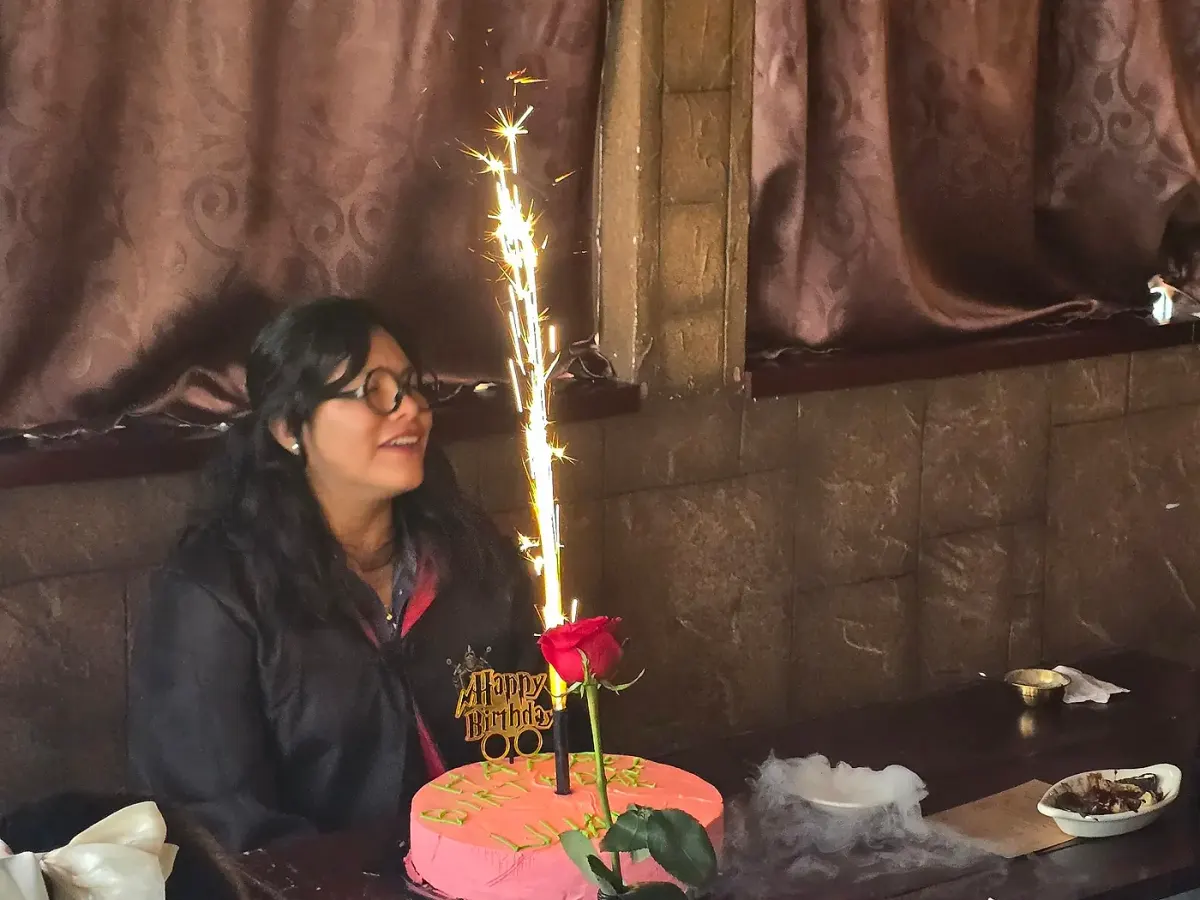 Festín Cumpleañero en Arcanum Domus: cumpleañera frente a su pastel con la vela-bengala encendida