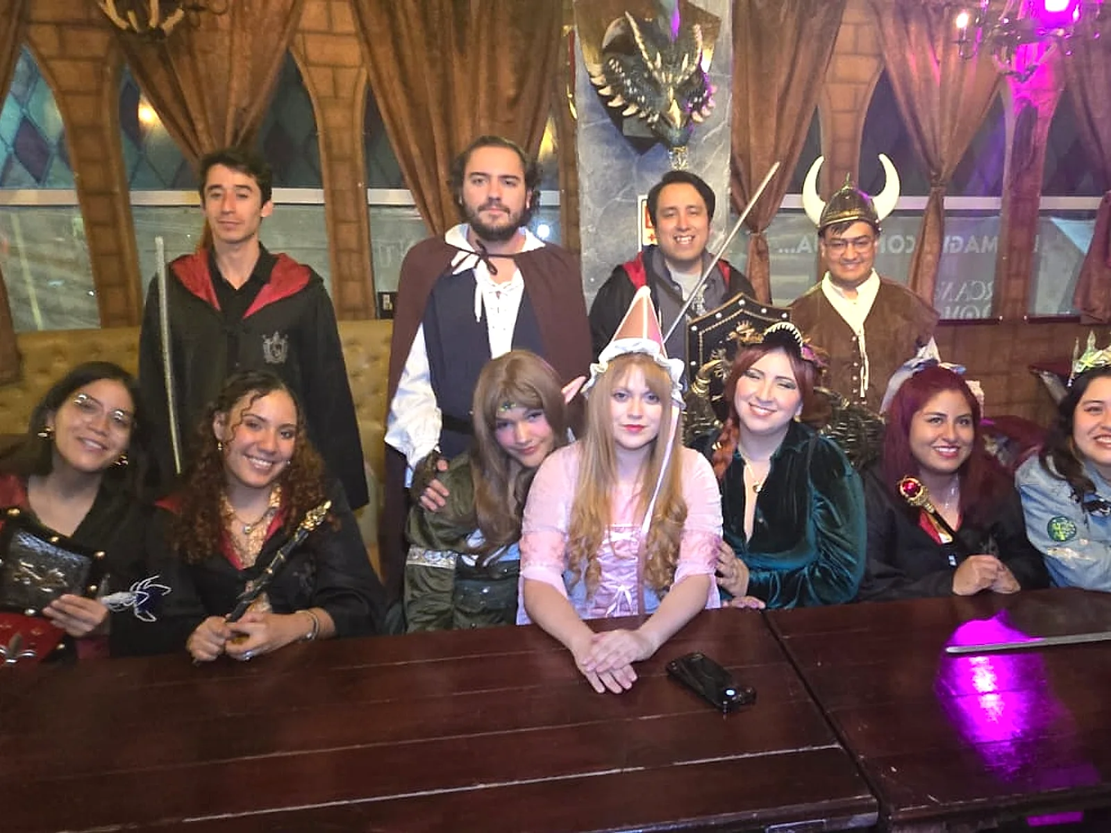 Grupo de amigos disfrazados en una mesa larga de Arcanum Domus