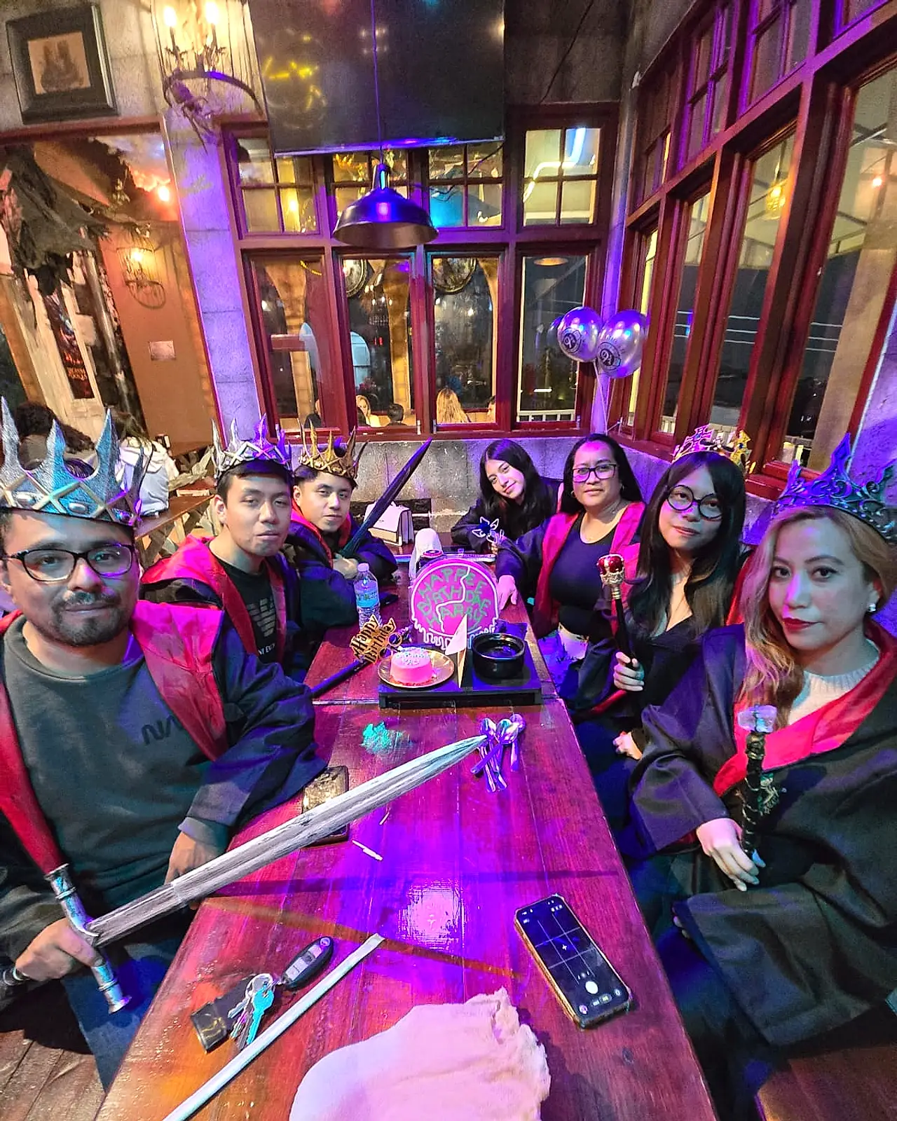 Grupo grande celebrando con coronas y espadas en el salón del Banquete Real de Arcanum Domus