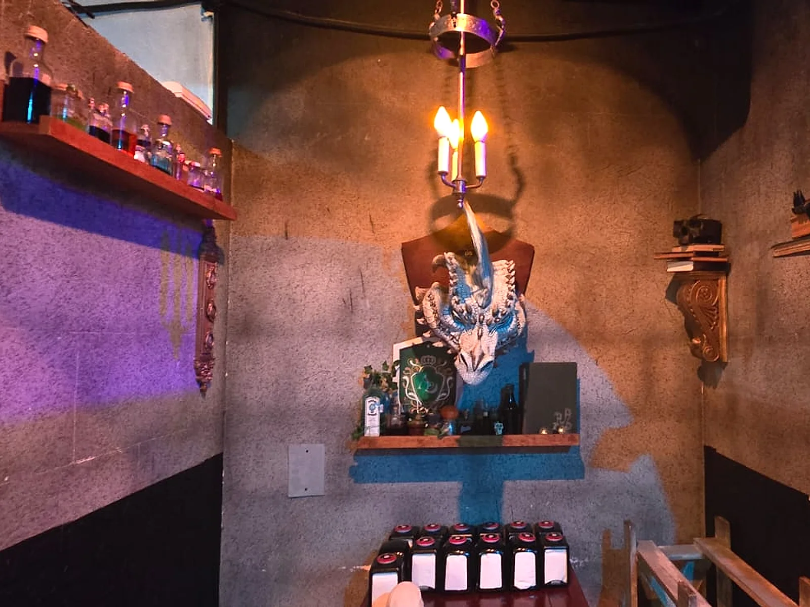 Nicho con escultura de dragón y velas en Arcanum Domus